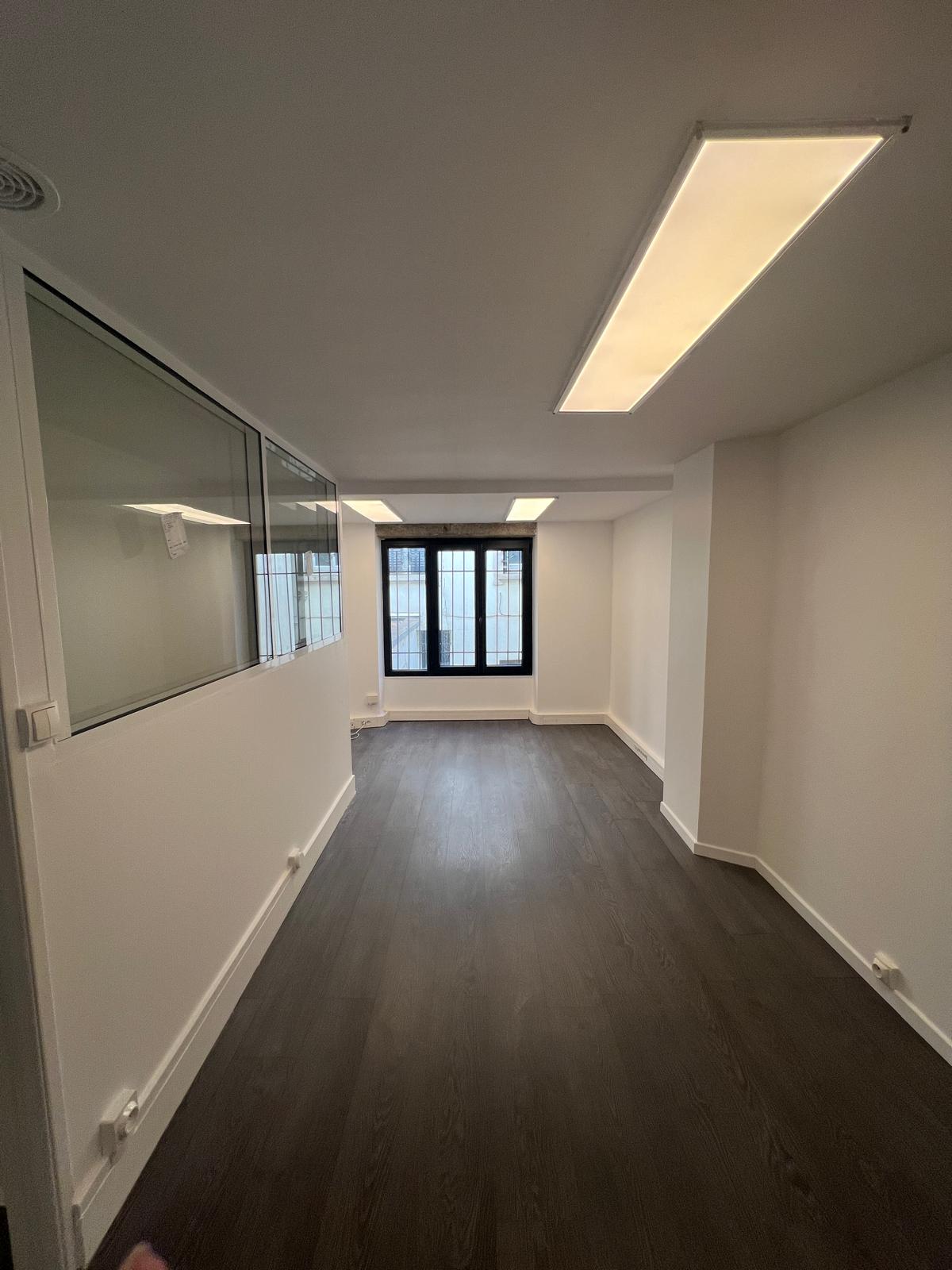 Photo d'un local vide avec des murs de couleur blanche et un parquet de couleur foncée.