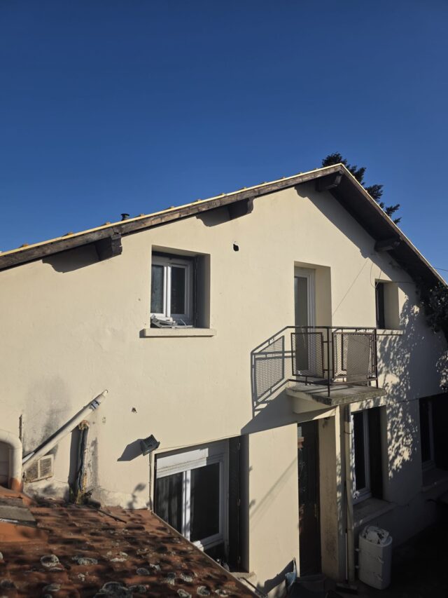Photo extérieure d'une maison avec une façade de couleur claire.