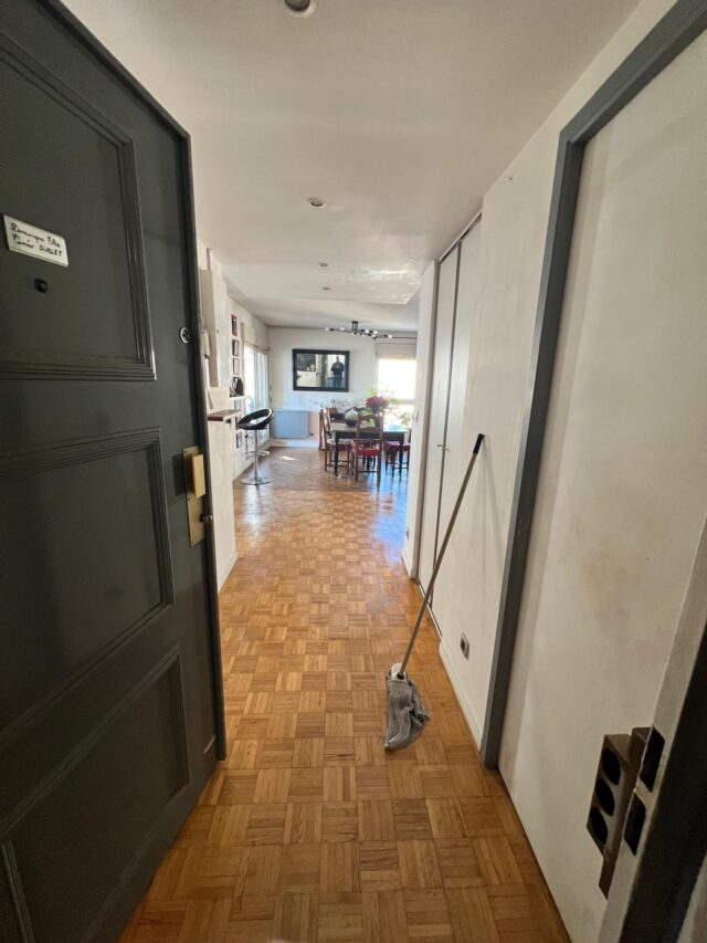 Photo d'un couloir d'un appartement avec un parquet de style empire en train d'être nettoyé.