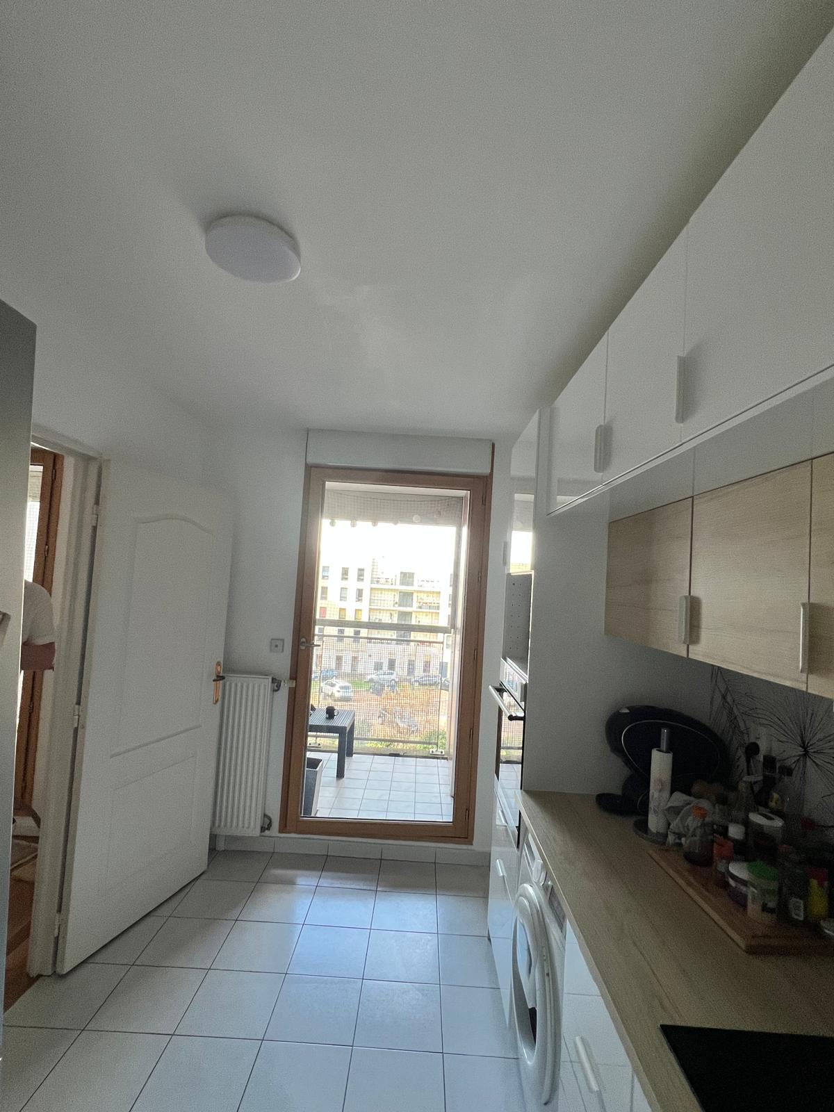 Photo de la cuisine d'un appartement avec une porte donnant sur un balcon extérieur.