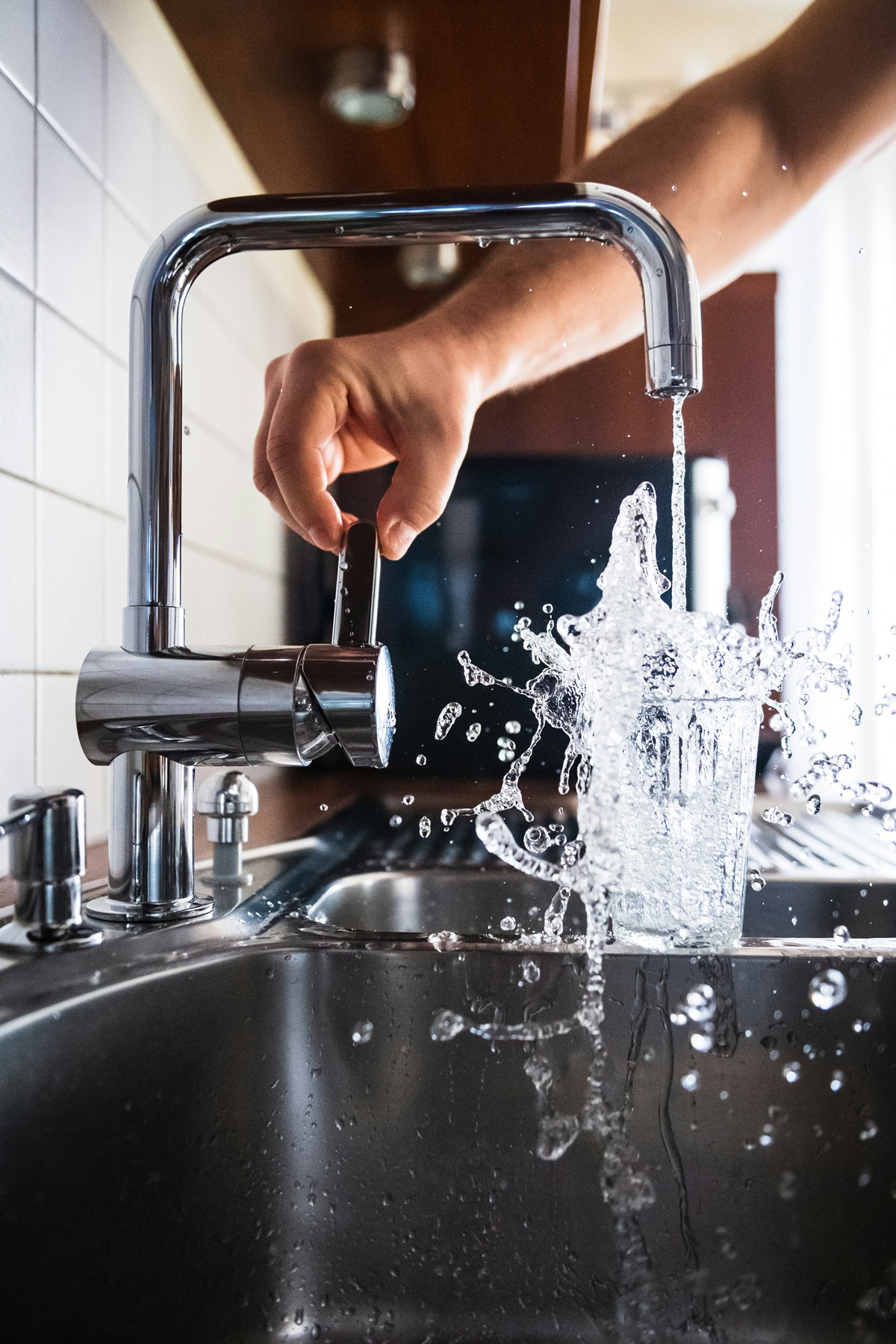 Photo d'un robinet de cuisine d'où de l'eau s'écoule pour remplir un verre.
