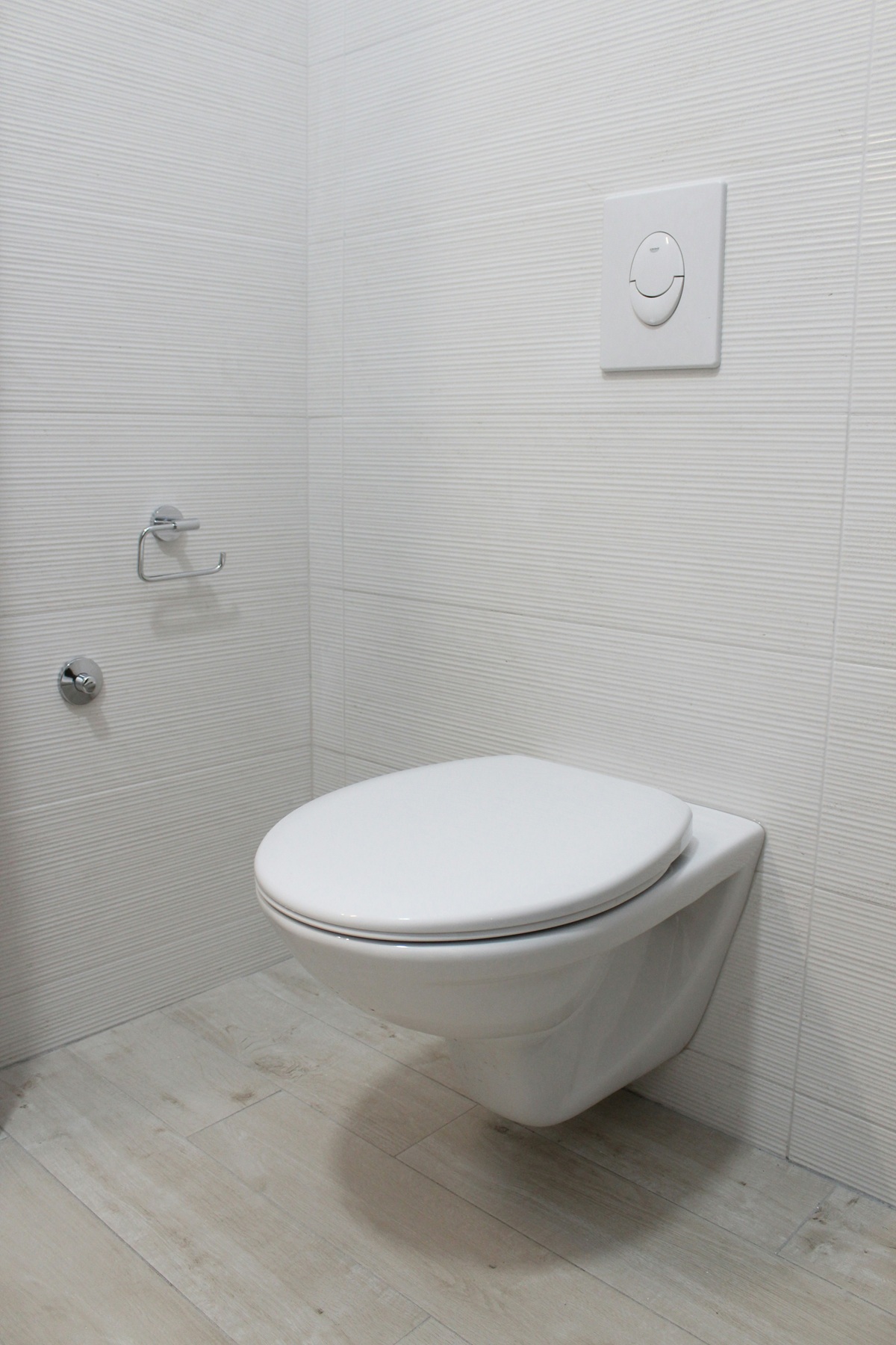 Photo de WC suspendu dans une pièce carrelée en blanc.