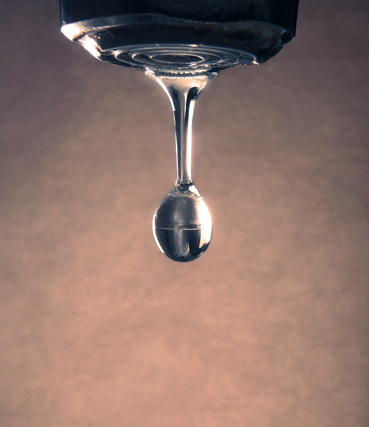 Photo d'une goutte d'eau s'écoulant d'un pommeau de douche.