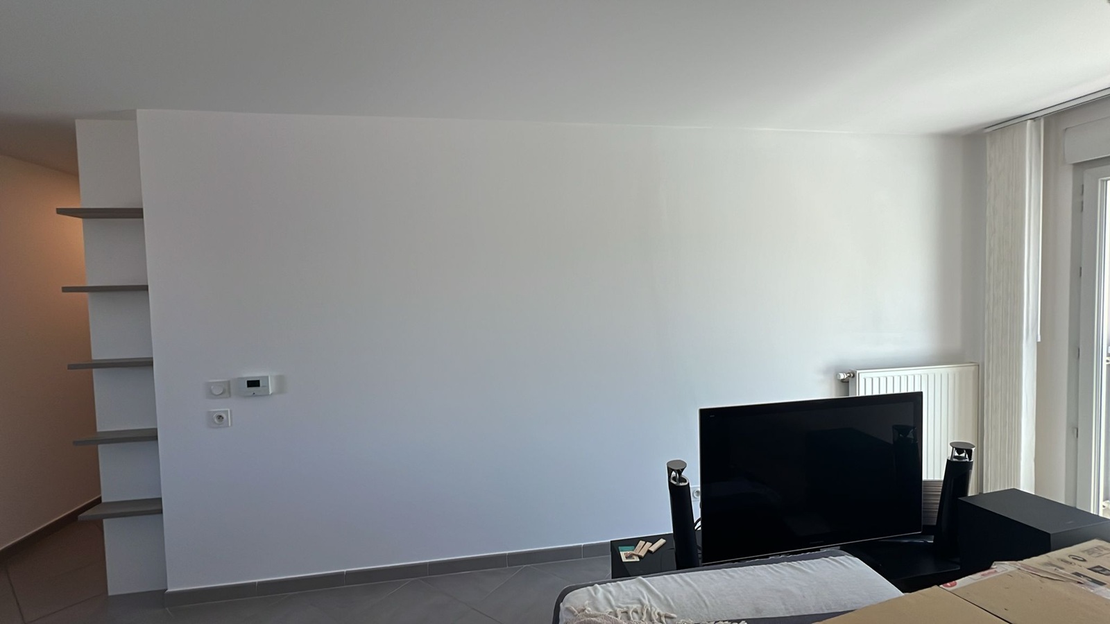 Photo d'un salon avec un thermostat mural et une télévision à écran plat.