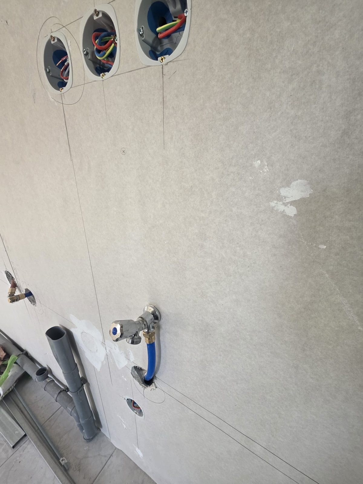 Photo d'un mur carrelé ou des réservations pour la plomberie et l'électricité ont été percées.