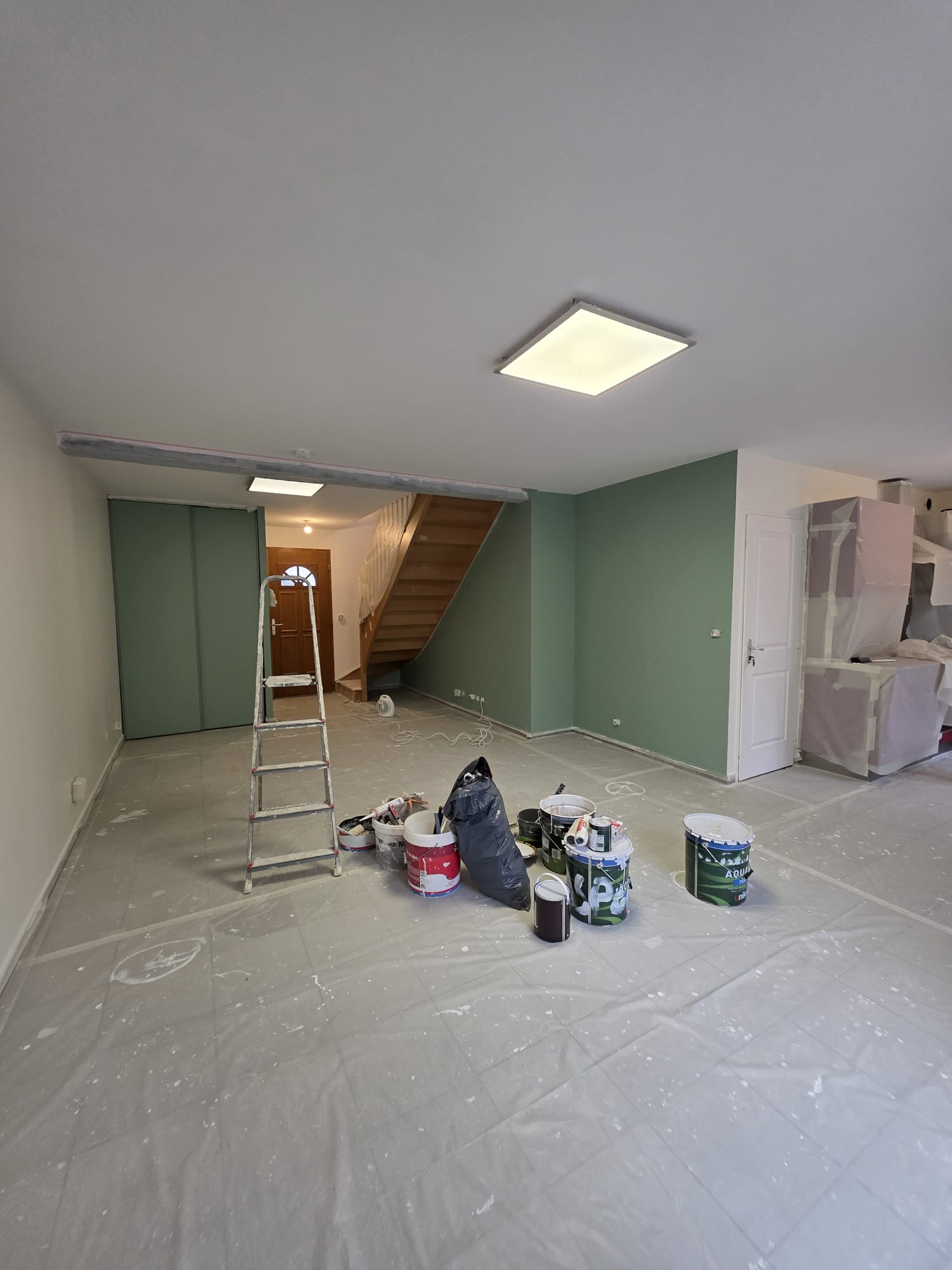 Photo d'un chantier de peinture où le sol et les meubles sont protégés.