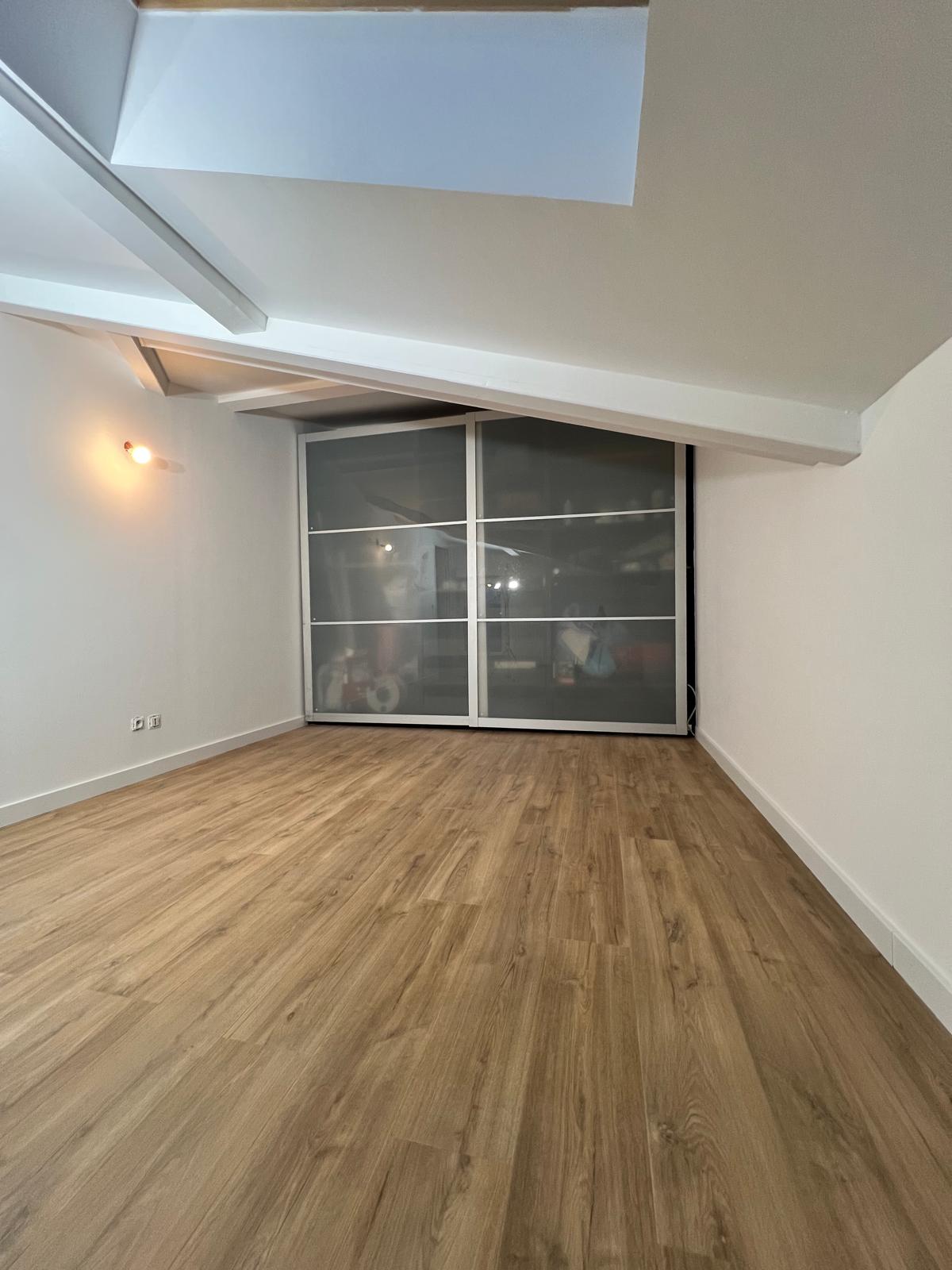 Photo d'une pièce rectangulaire aux murs blancs avec une séparation en panneaux coulissants en verre.