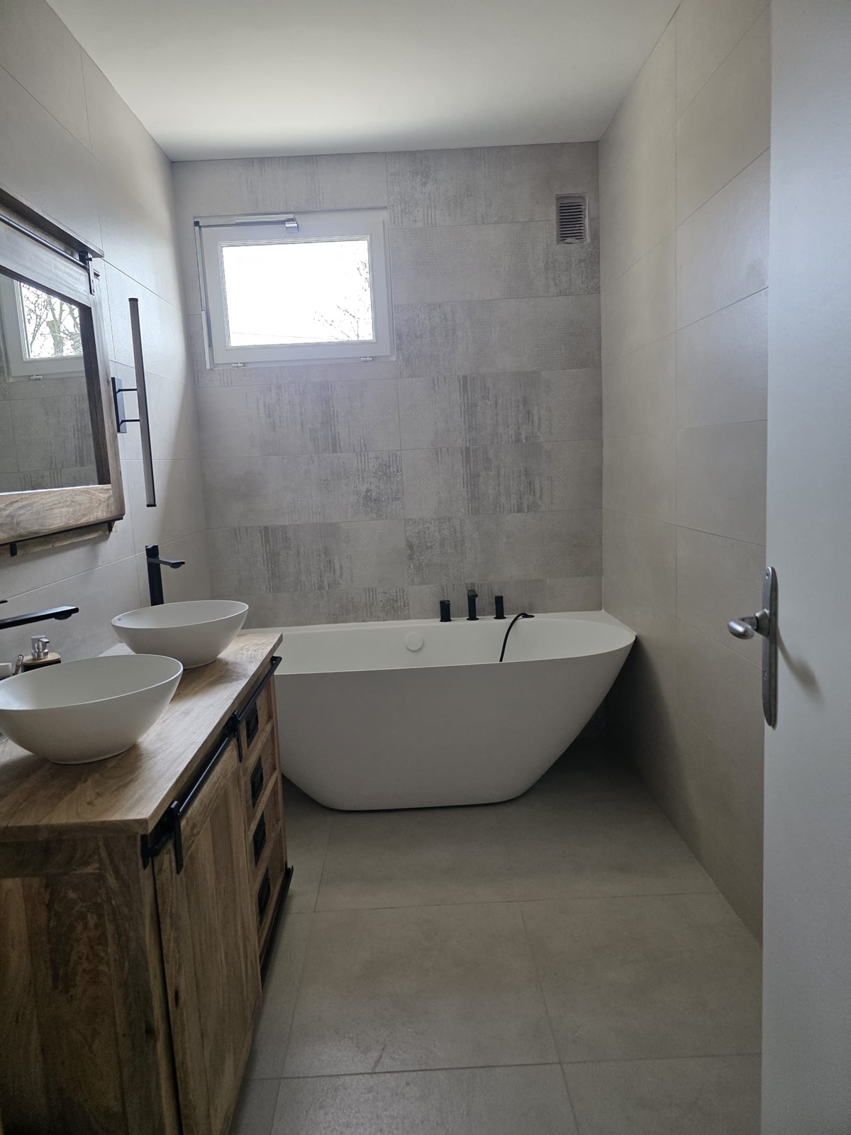 Photo d'une salle de bains avec une baignoire moderne, un meuble double vasque et des grands carrelages sur les murs et les sols.