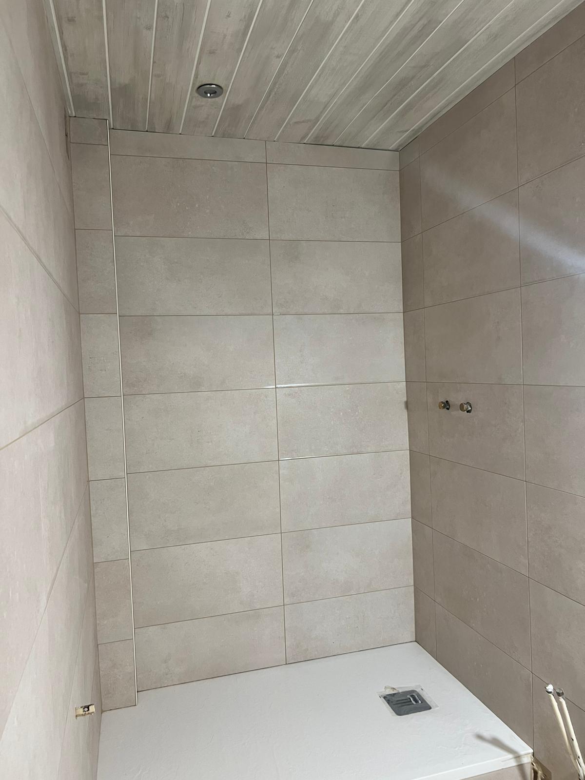 Photo d'une douche moderne avec un receveur plat et des grands carrelages rectangulaires de couleur beige.